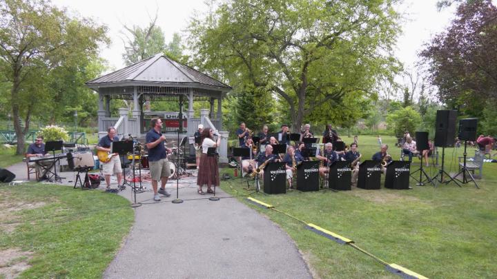 A band performs outside near a pavilion. 